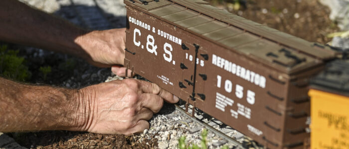 Mark Brown sets a train car in his garden railroad.