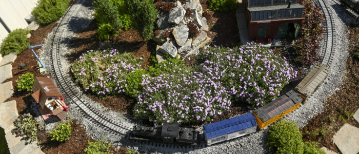 A train rides around the Burningtree Brewery and Burningtree station of Barb and Mark Brown’s garden railroad.
