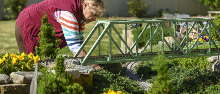 Barb Brown pulls little weeds from the manicured landscaping of her garden railroad.