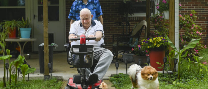Samuel Jones walks with Senior Companion program volunteer Raymond Ruth, back, Grizz and Patches, in Jones’ backyard.