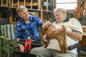 Senior Companion program volunteer Raymond Ruth, left, and Samuel Jones pet one of Jones’ dogs, Grizz, as they spend time together.