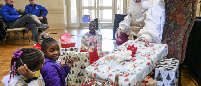 Santa Claus (Paul Martin) gives presents to children during the Kiwanis Club’s Christmas lunch. [JERONIMO NISA/DECATUR DAILY]